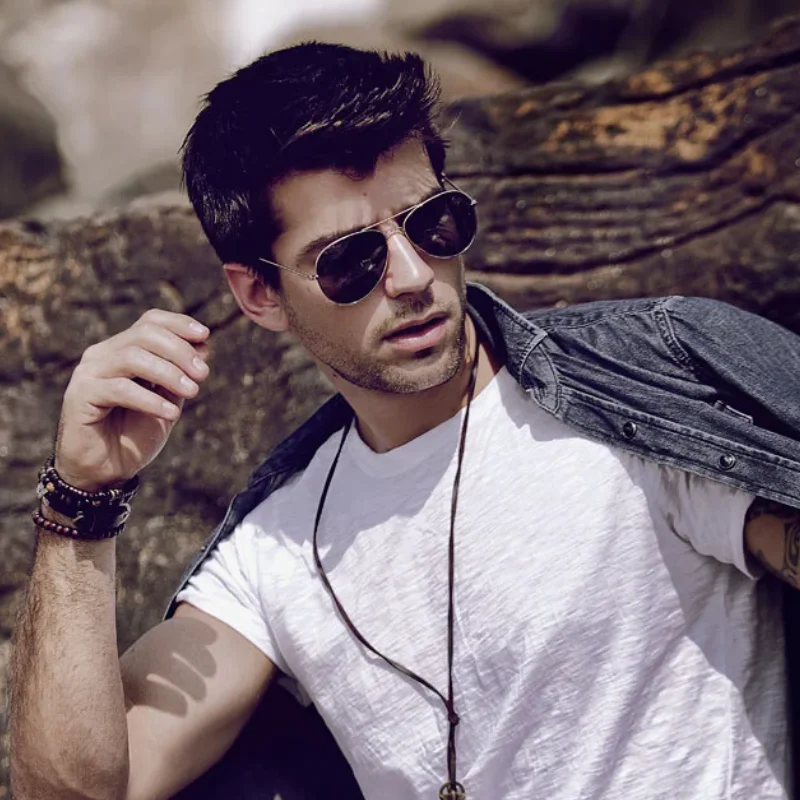 Featured fashion photography retouching portfolio highlight showing a male model wearing sunglasses and a denim shirt sitting on rocks