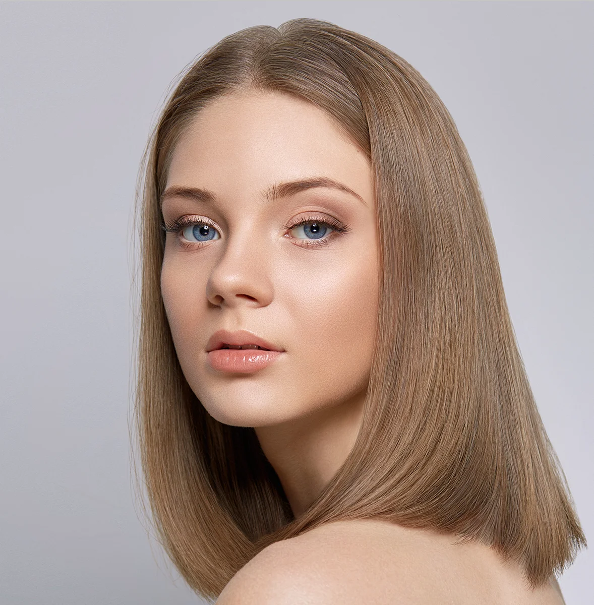 Clean natural makeup beauty portrait retouching showing a model with straight hair and striking blue eyes