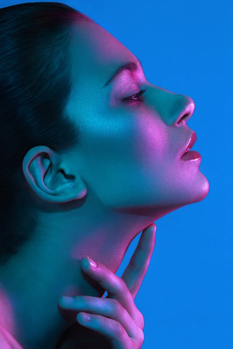 Neon lighting beauty portrait retouching showing a model's profile illuminated in vibrant pink and blue light