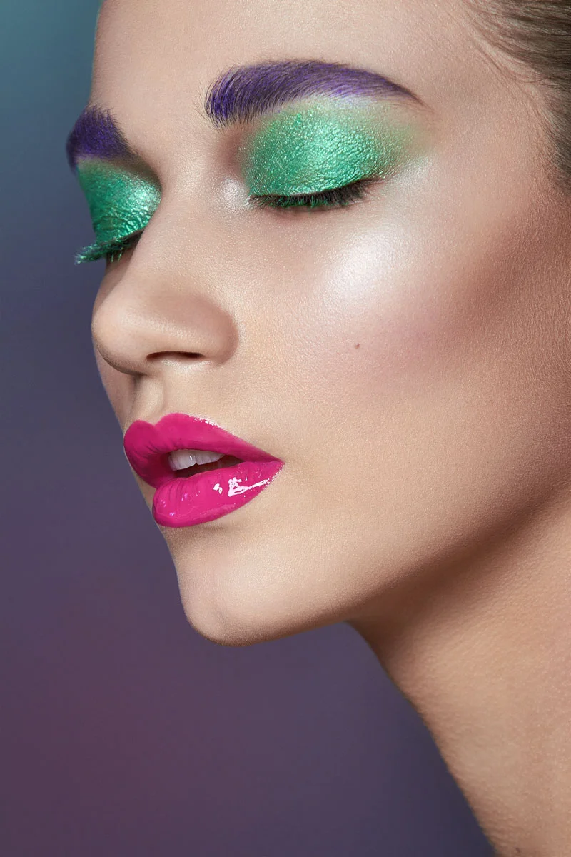 Close-up beauty portrait retouching of a model with hot pink glossy lips and green eyeshadow