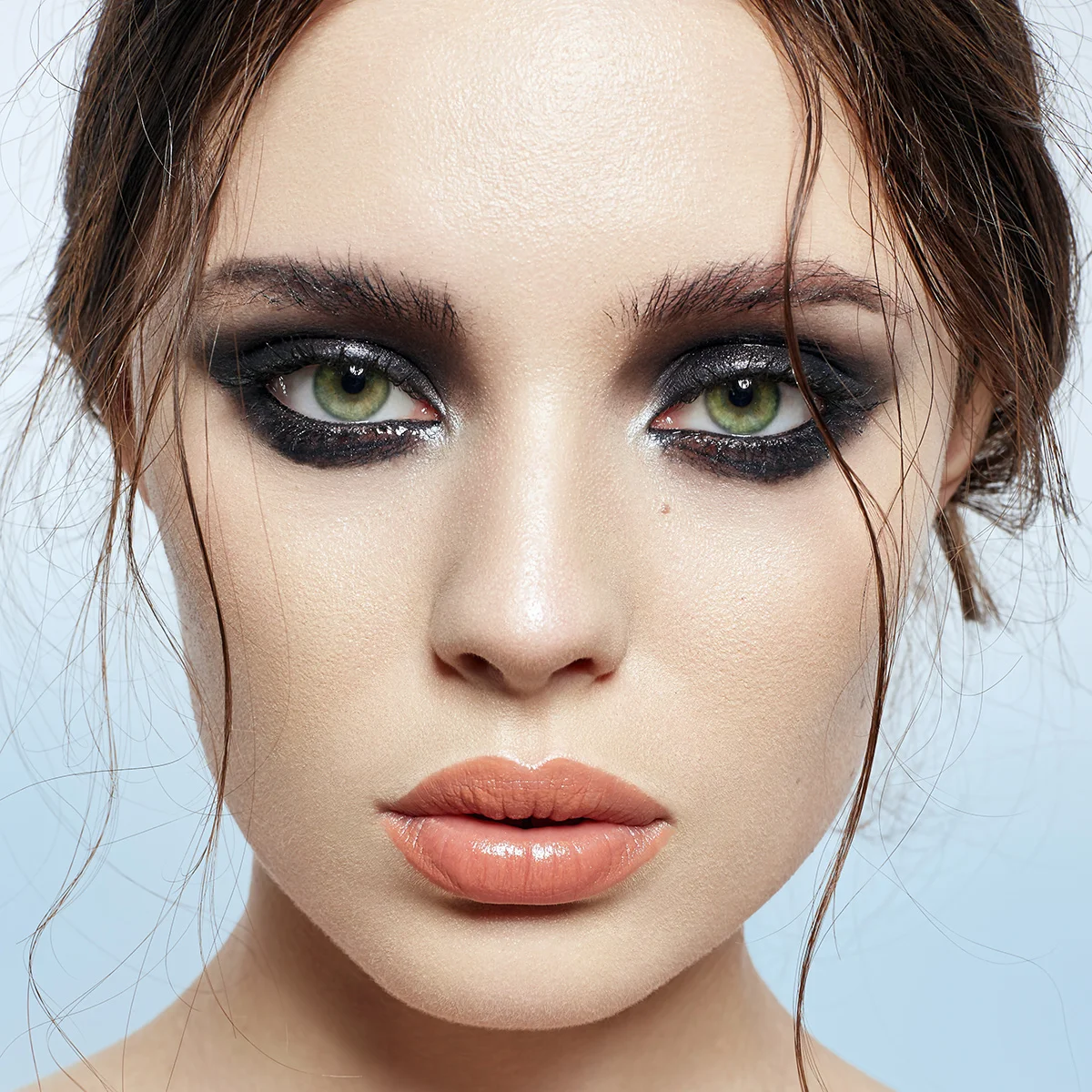 High-end beauty portrait retouching showing close-up of a model with green eyes and dramatic smokey eye makeup