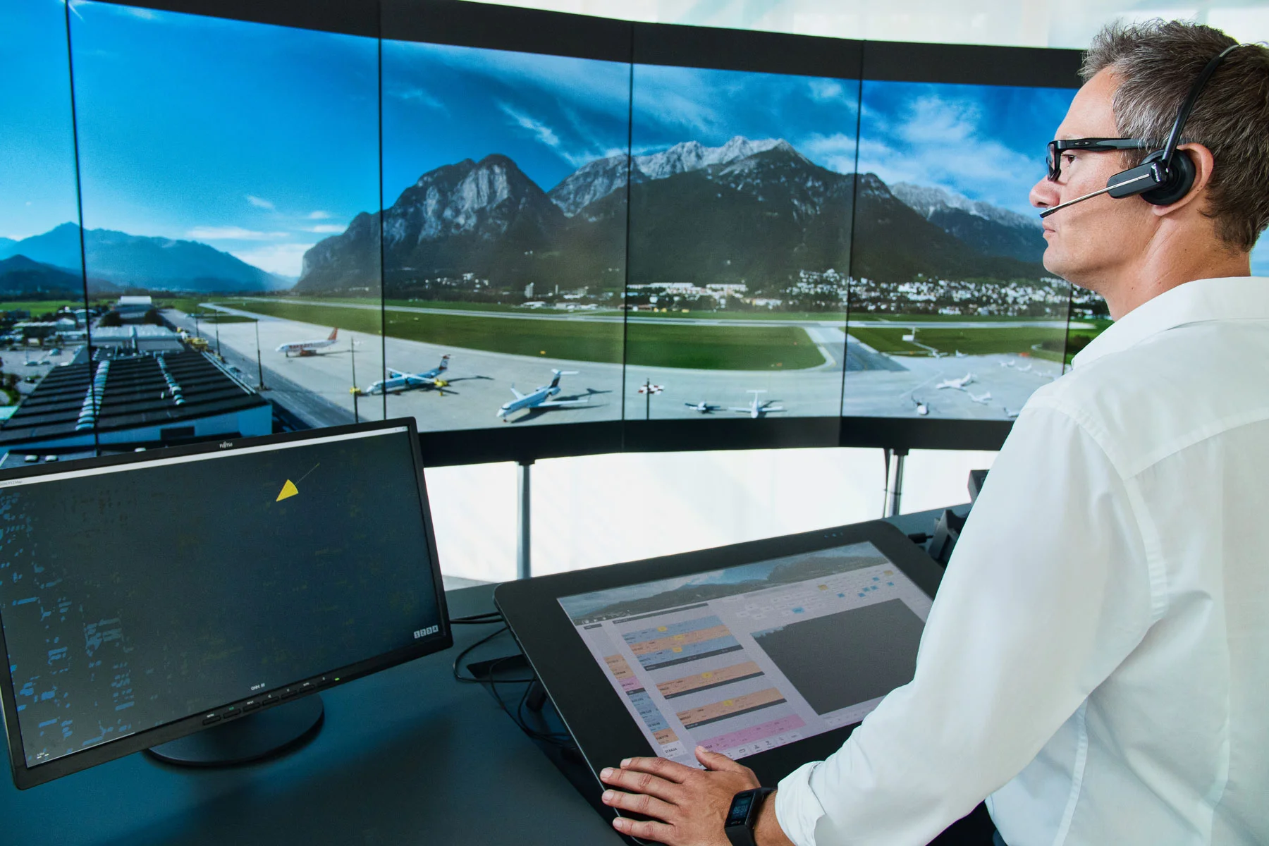 Air traffic control operator headshot retouching showing professional specialist with headset in front of airport radar screens