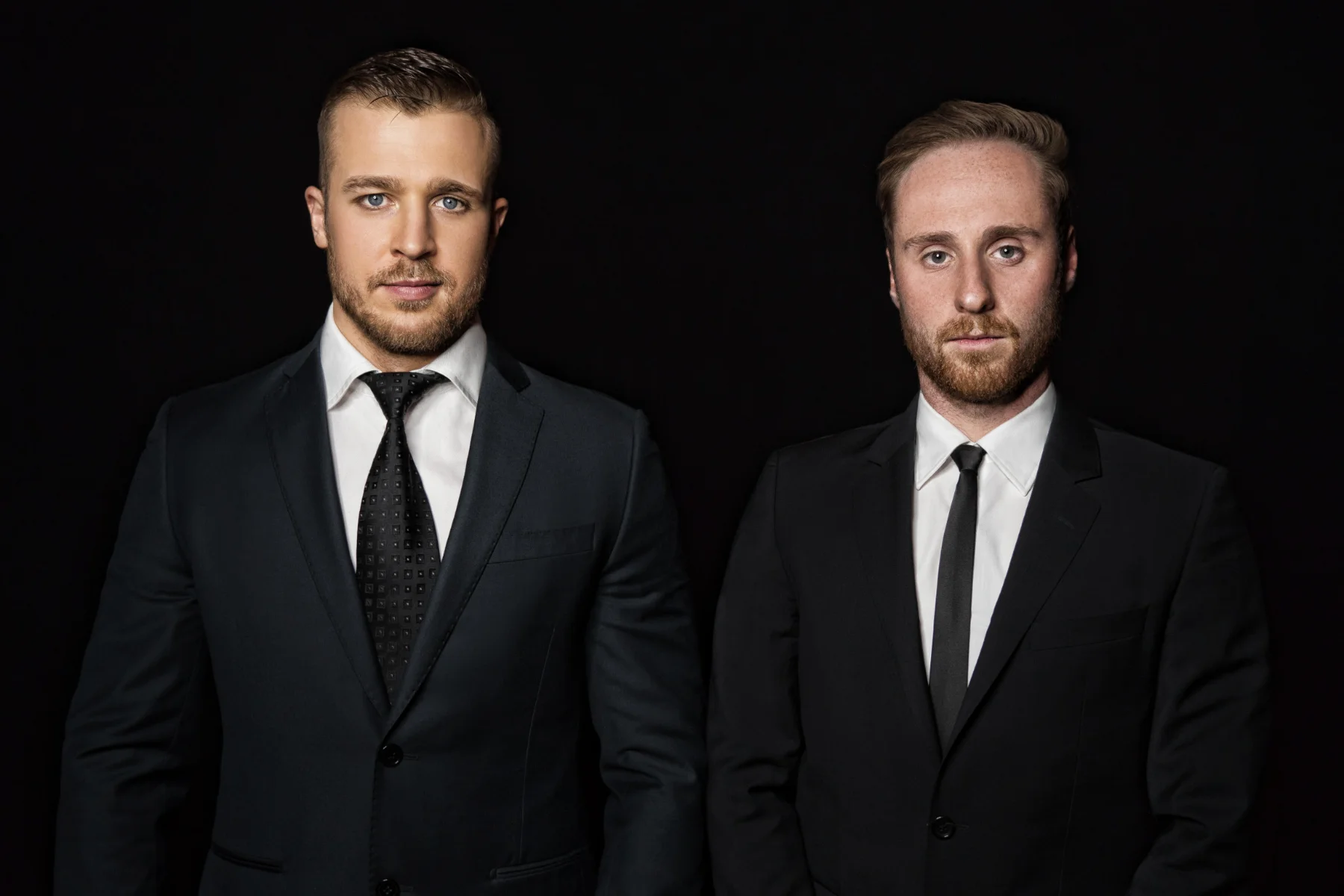 Corporate business portrait retouching of two male partners in black suits on a dark background