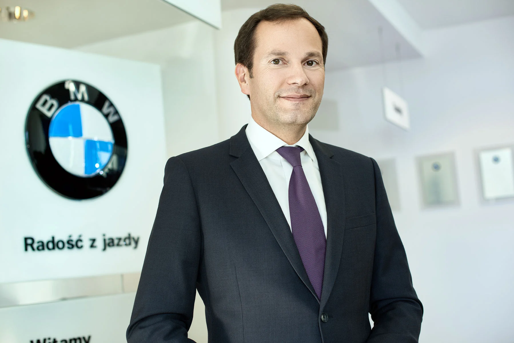 Corporate business portrait retouching of a professional businessman in a dark suit with corporate interior background