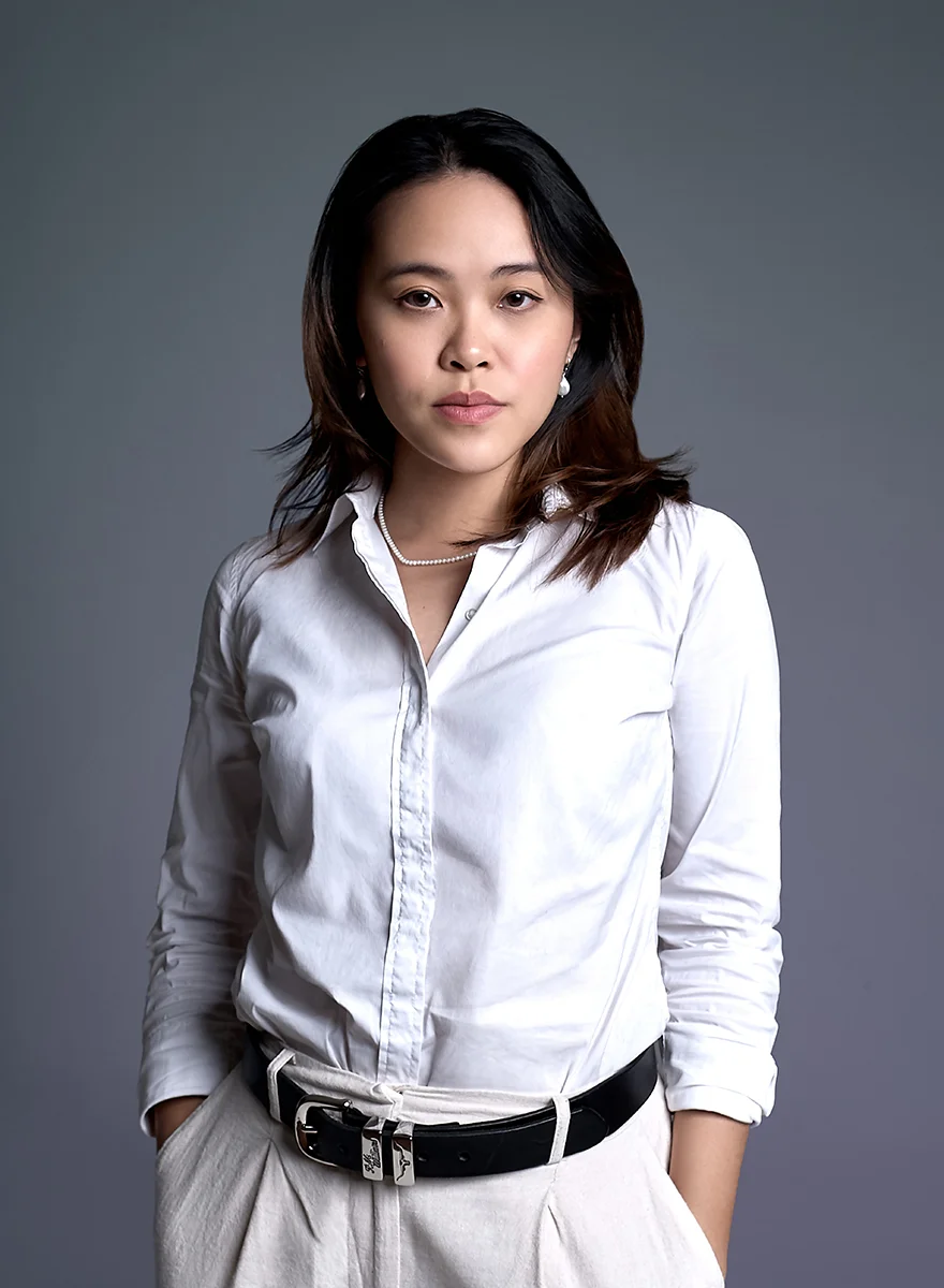 Professional business portrait retouching of an Asian woman wearing a white button-down shirt and black belt with hands in pockets