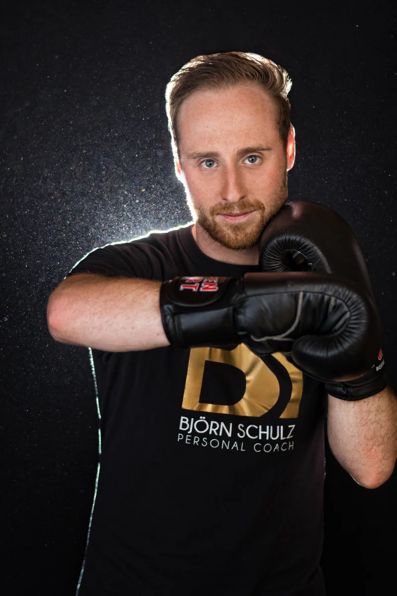 Personal boxing coach portrait retouching of Björn Schulz in black gloves on a dark background