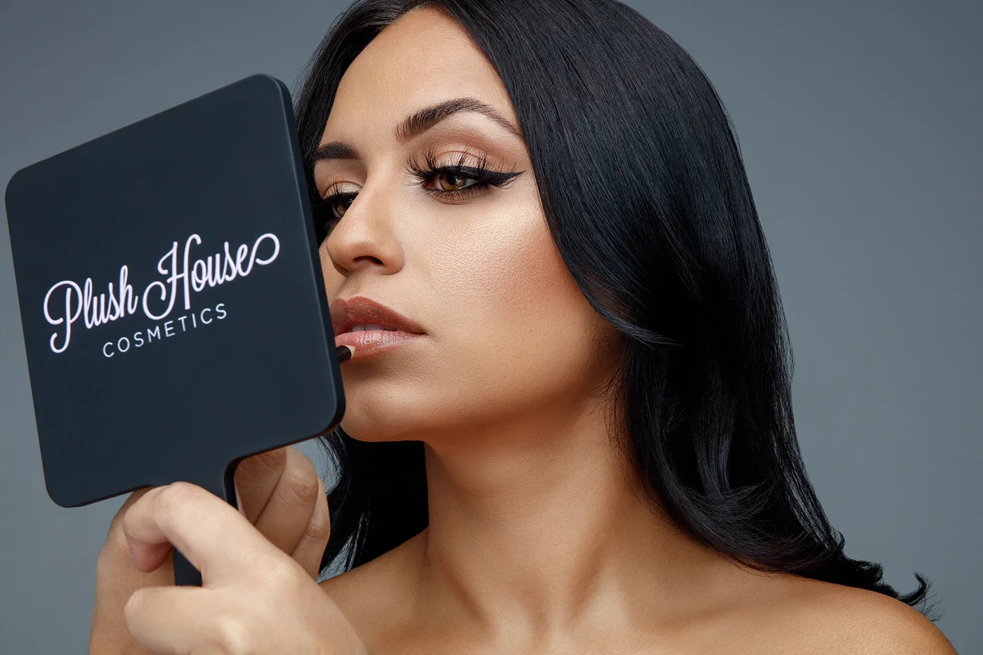 Cosmetics advertising campaign portrait retouching of a model applying lipstick while looking into a makeup mirror